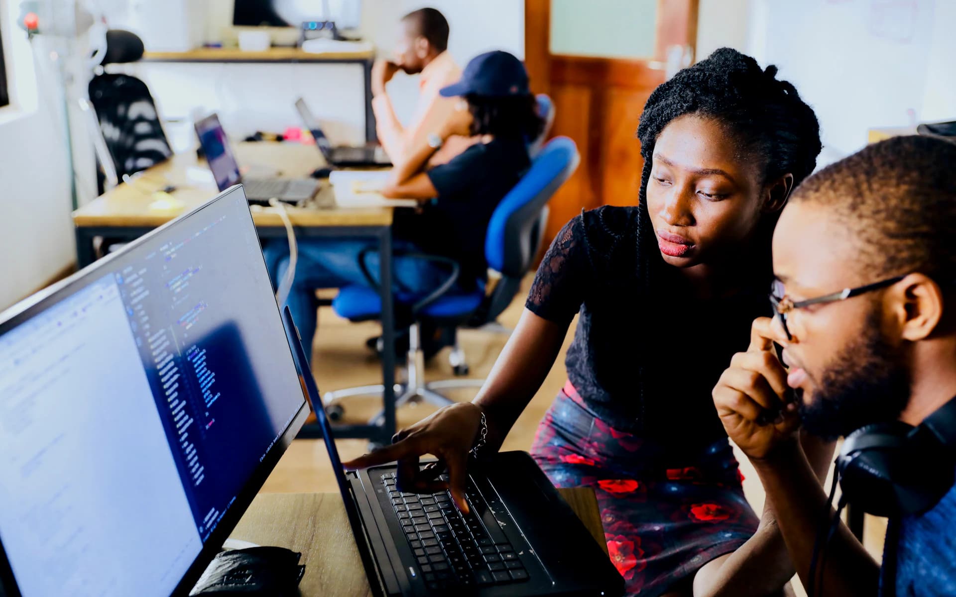 African software developers collaborating around a computer in a working studio.
